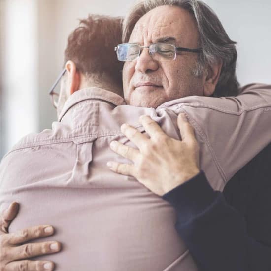 Two bespectacled men hugging each other